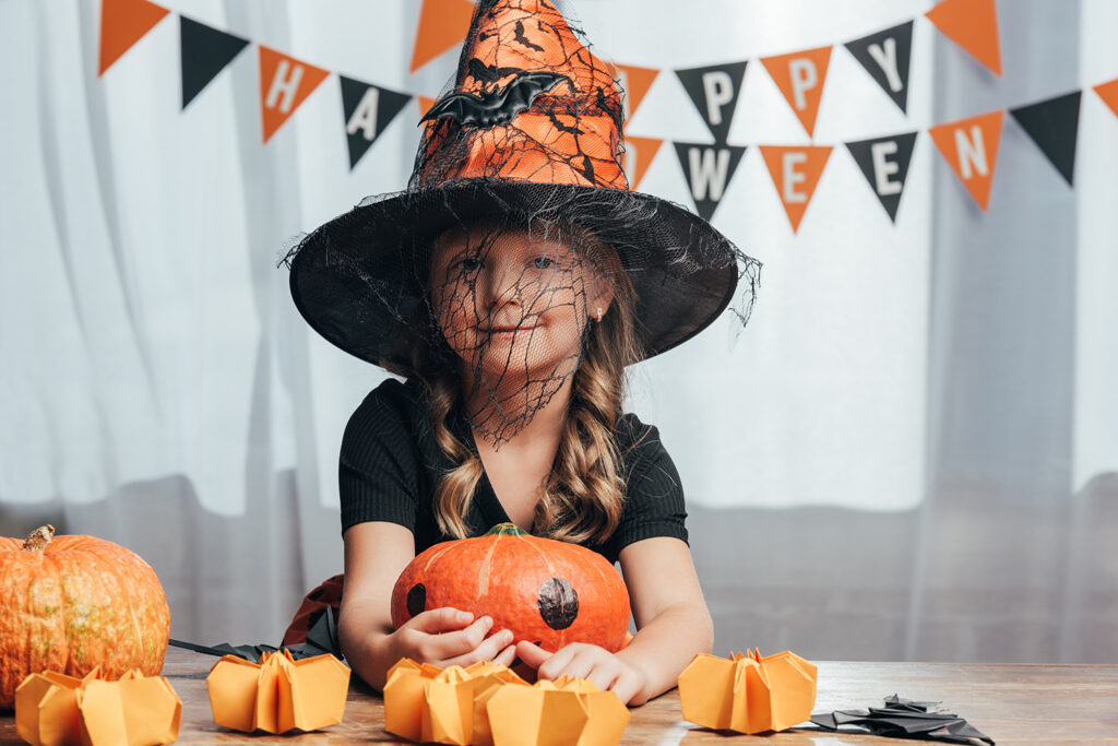 portrait of adorable kid in witch halloween costume at tabletop